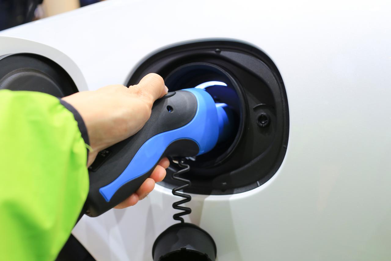 a hand fueling a car with electrcitiy