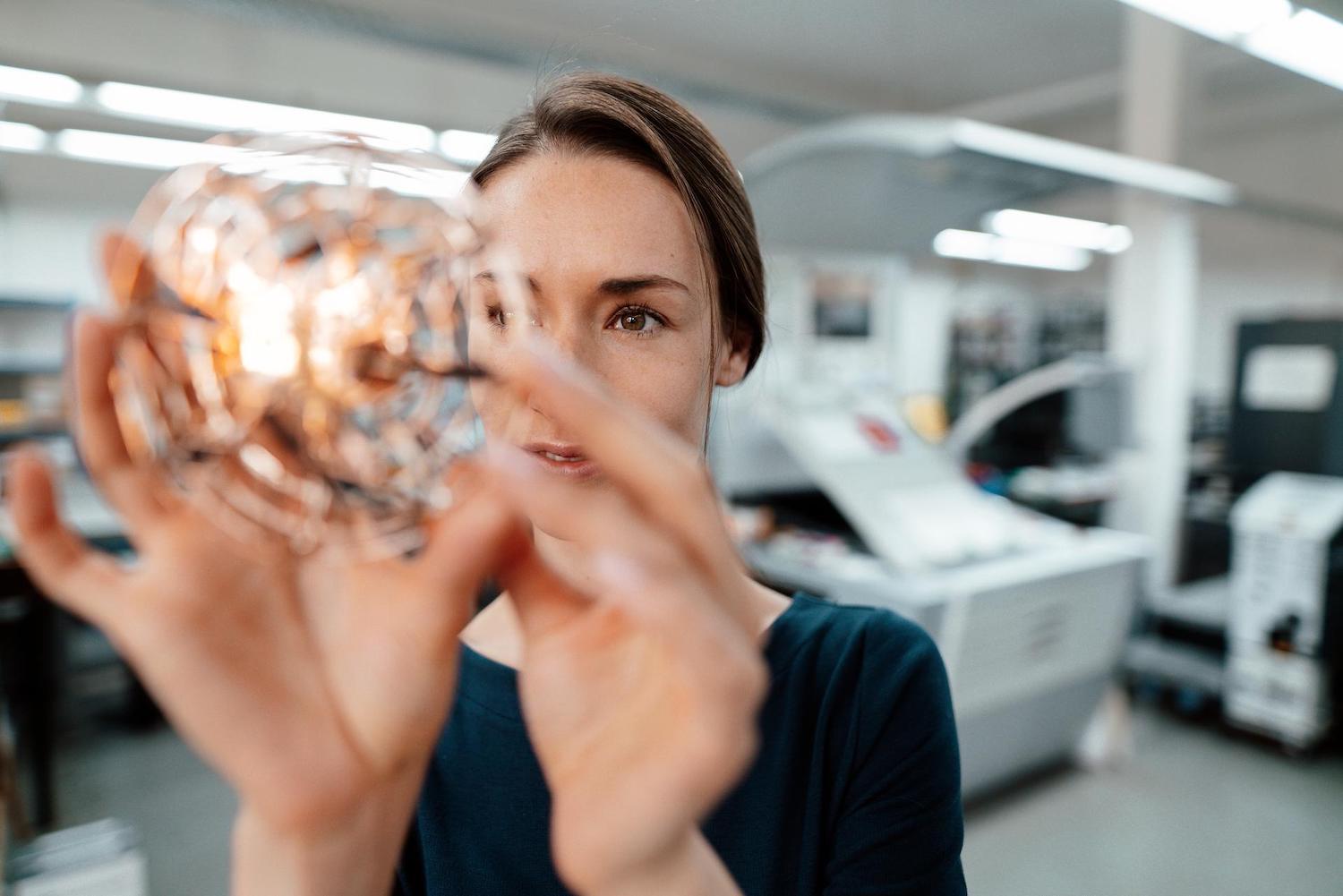 Woman looking into a round glass shape with lights in it
