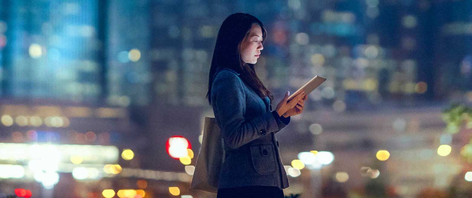 woman on a tablet in the city with blurry lights background
