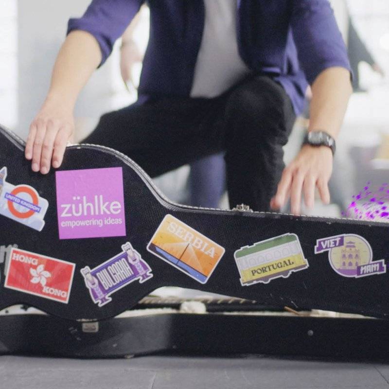 Guitar case with lots of Zühlke stickers that show their different office locations being opened.