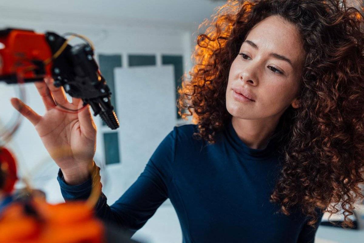 Female engineer examining a robotic arm in an office